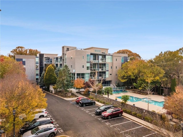 view of building exterior with a community pool and uncovered parking