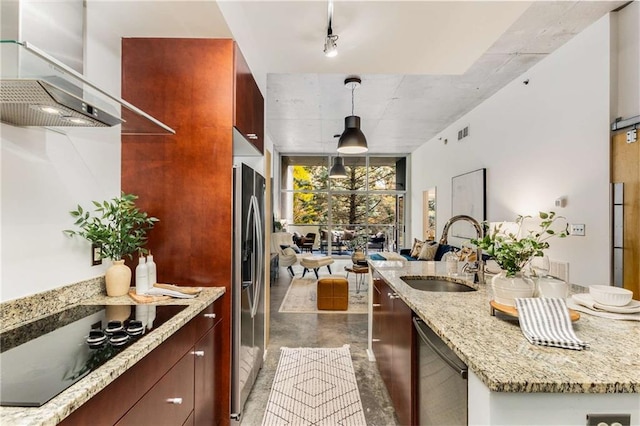 kitchen featuring wall chimney range hood, appliances with stainless steel finishes, a sink, visible vents, and pendant lighting