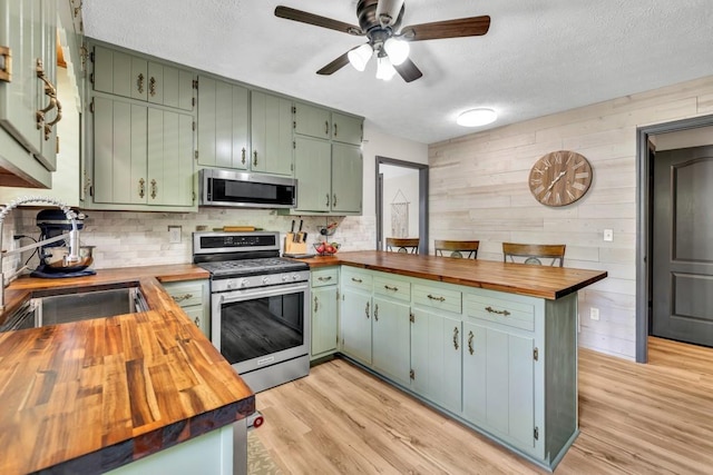 6127 Yellow Creek Rd, Murrayville, GA 30564 - kitchen with butcher block countertops, appliances with stainless steel finishes, a sink, wooden walls, and a textured ceiling