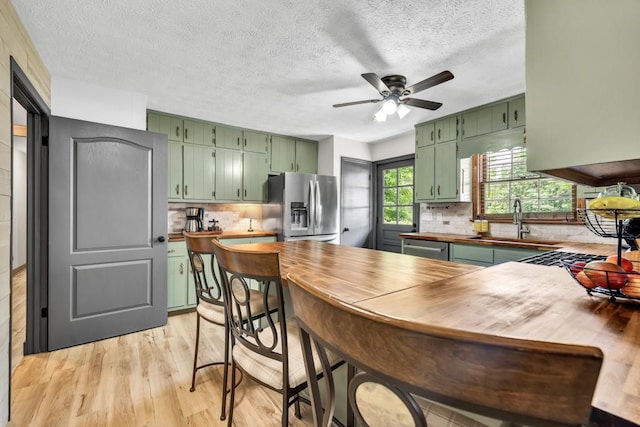 6127 Yellow Creek Rd, Murrayville, GA 30564 - kitchen with green cabinetry, appliances with stainless steel finishes, a sink, light wood-style floors, and a textured ceiling