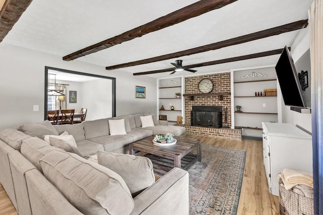 6127 Yellow Creek Rd, Murrayville, GA 30564 - living room featuring light wood-type flooring, beam ceiling, a ceiling fan, a fireplace, and built in shelves