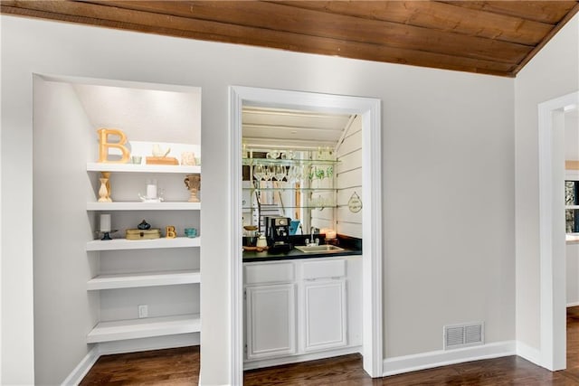 bar with baseboards, visible vents, a sink, indoor wet bar, and wooden ceiling