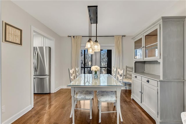 dining space featuring dark wood-style floors, a notable chandelier, and baseboards