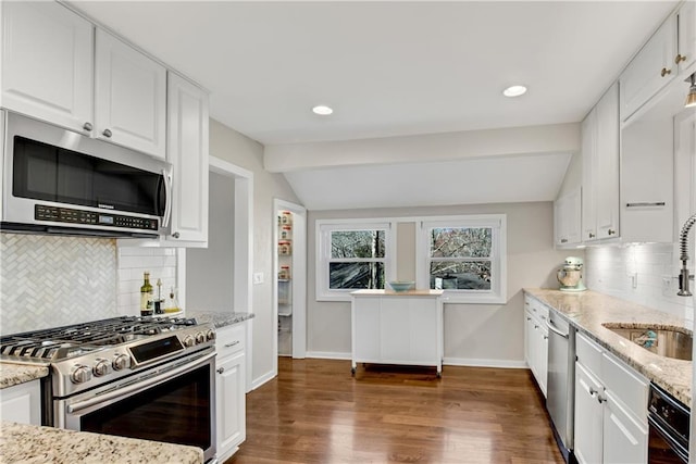 kitchen with a sink, vaulted ceiling, white cabinetry, and stainless steel appliances