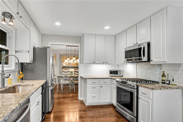 kitchen featuring a sink, white cabinetry, appliances with stainless steel finishes, light stone countertops, and dark wood-style flooring