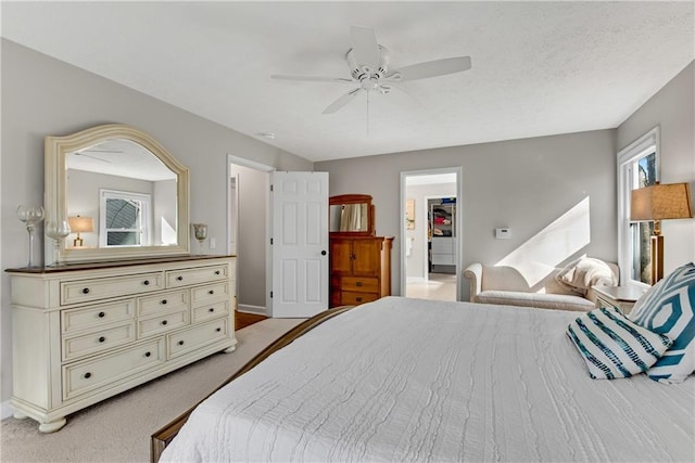 bedroom featuring a walk in closet, a textured ceiling, a ceiling fan, and light carpet