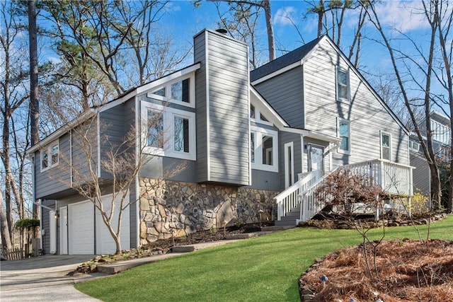 view of side of property with stone siding, a lawn, a chimney, and driveway