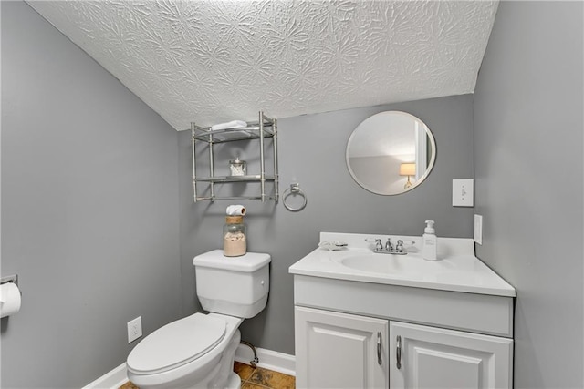 bathroom featuring baseboards, toilet, vanity, and a textured ceiling