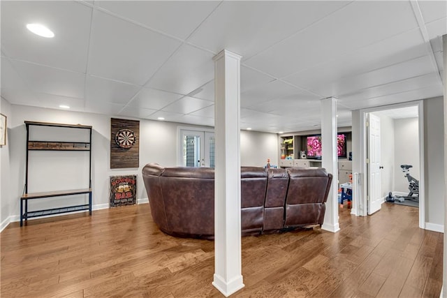 living room featuring wood finished floors, baseboards, decorative columns, recessed lighting, and a paneled ceiling