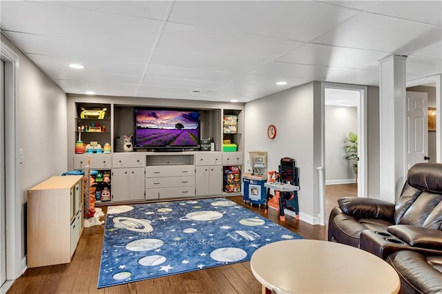 living area featuring a drop ceiling, recessed lighting, baseboards, and wood finished floors