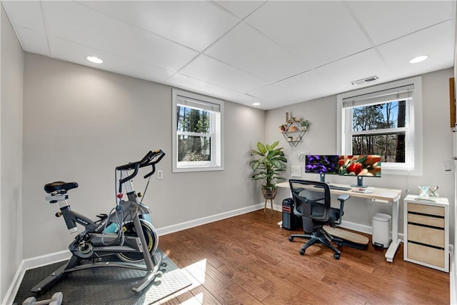 home office with visible vents, a drop ceiling, baseboards, and wood finished floors