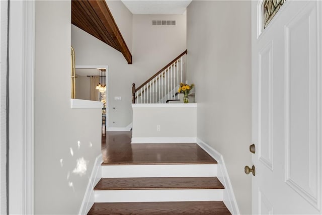 stairway featuring visible vents, baseboards, and wood finished floors