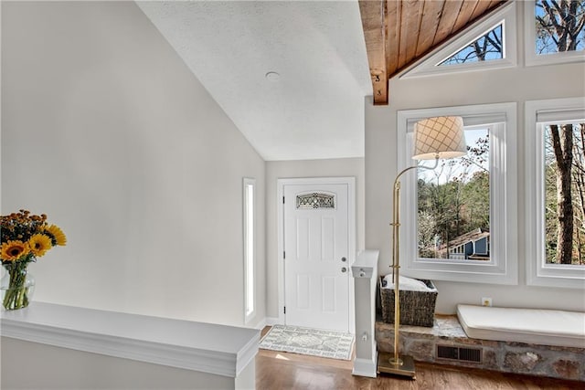 entryway featuring vaulted ceiling, wood finished floors, visible vents, and a textured ceiling