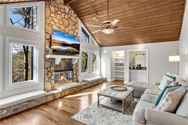 living area with high vaulted ceiling, a ceiling fan, wood finished floors, a fireplace, and wood ceiling