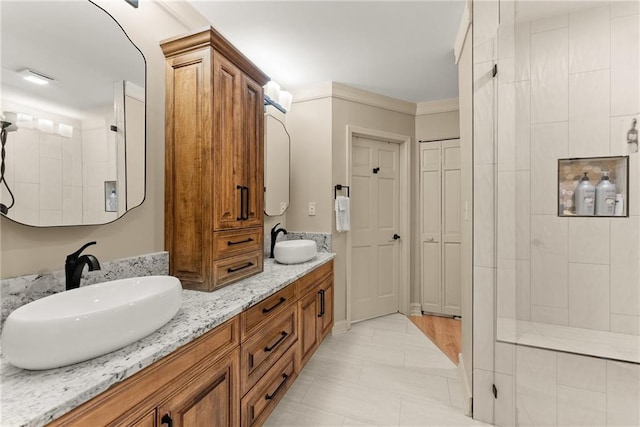 full bath featuring double vanity, tiled shower, a sink, and tile patterned floors