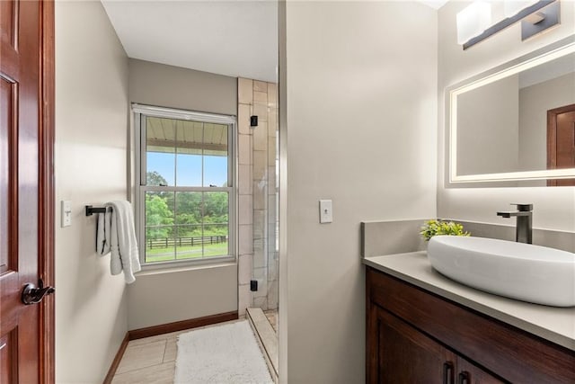 bathroom featuring a stall shower, tile patterned floors, baseboards, and vanity