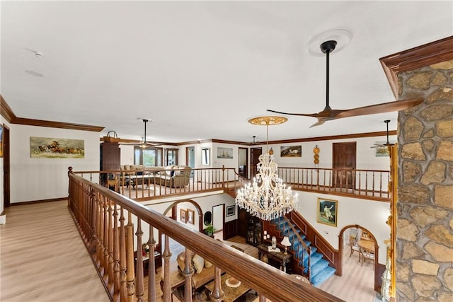 interior space featuring light wood finished floors, baseboards, crown molding, an upstairs landing, and a notable chandelier