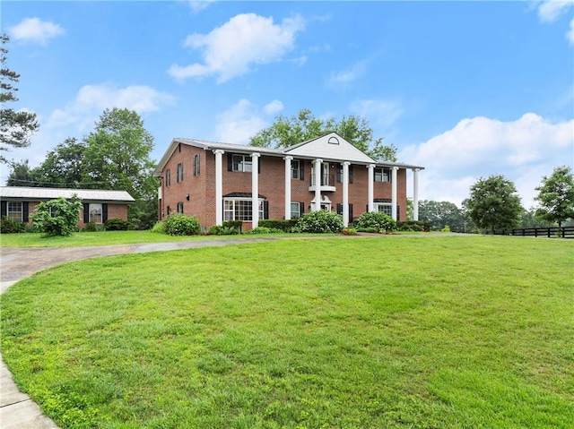 neoclassical home with brick siding and a front yard