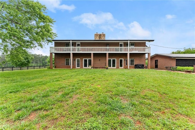 rear view of property featuring brick siding, a chimney, fence, and a yard