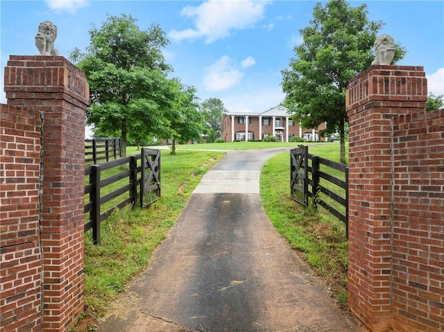 view of gate with fence and a lawn