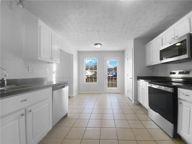 kitchen with light tile patterned floors, a textured ceiling, stainless steel appliances, a sink, and white cabinets