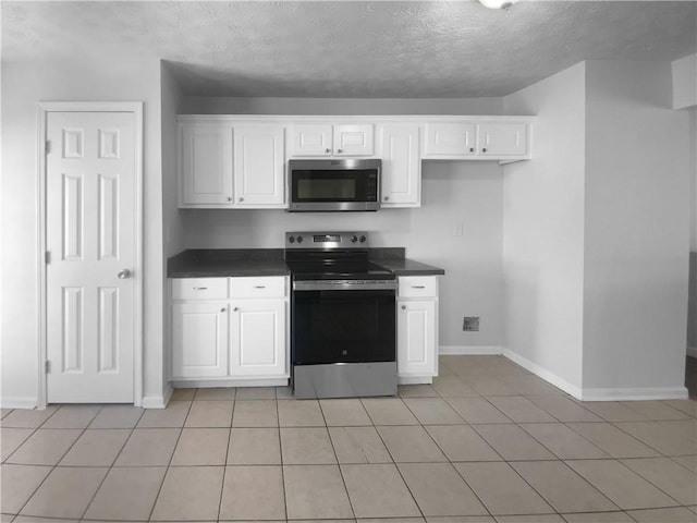 kitchen with dark countertops, baseboards, white cabinets, and stainless steel appliances