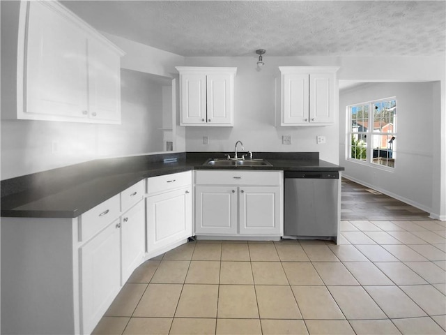 kitchen featuring a sink, dark countertops, stainless steel dishwasher, and light tile patterned flooring