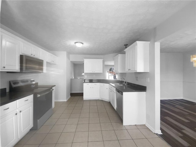 kitchen featuring stainless steel appliances, dark countertops, white cabinets, a sink, and a textured ceiling