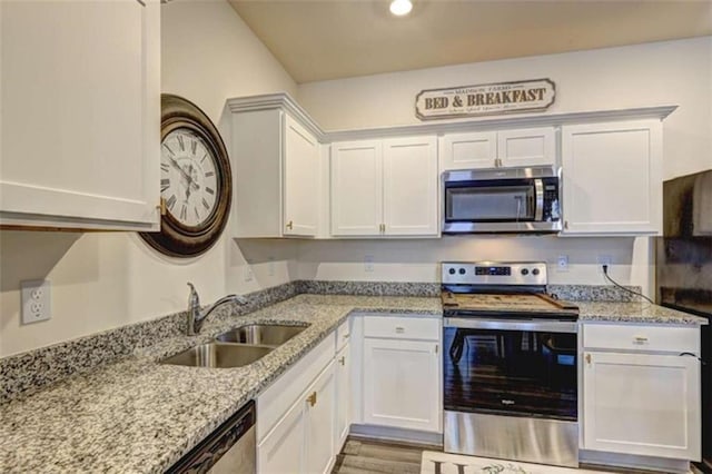 kitchen with light stone countertops, light wood-style flooring, a sink, white cabinets, and appliances with stainless steel finishes