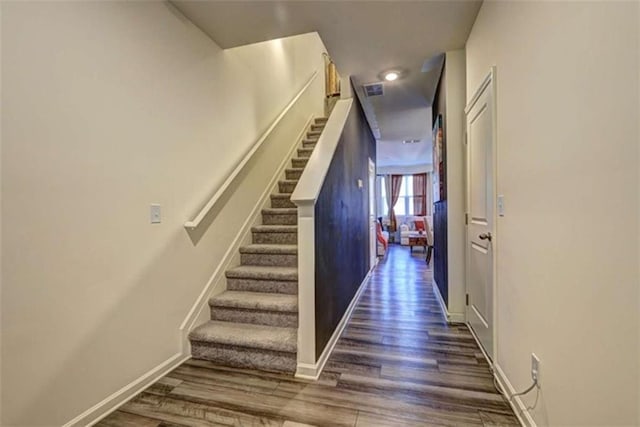 staircase with visible vents, baseboards, and wood finished floors