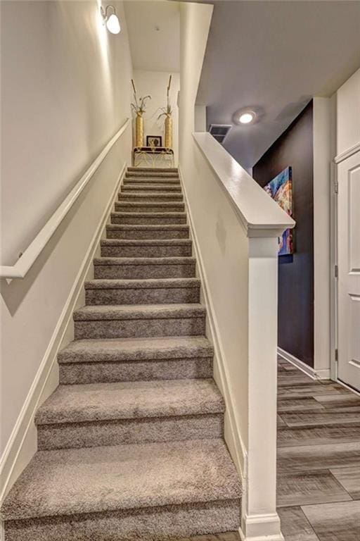 staircase with visible vents, wood finished floors, and baseboards