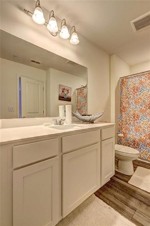 bathroom featuring a shower with shower curtain, visible vents, toilet, and vanity