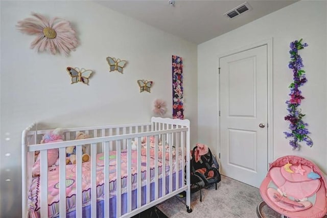 bedroom featuring a nursery area, visible vents, and carpet