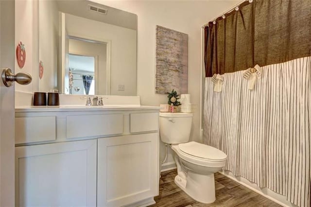 bathroom featuring vanity, toilet, wood finished floors, and visible vents