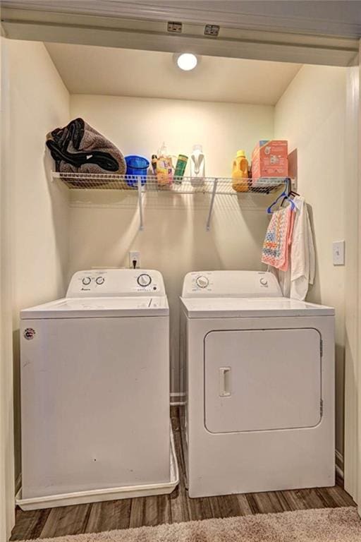 clothes washing area featuring laundry area, wood finished floors, and washing machine and clothes dryer