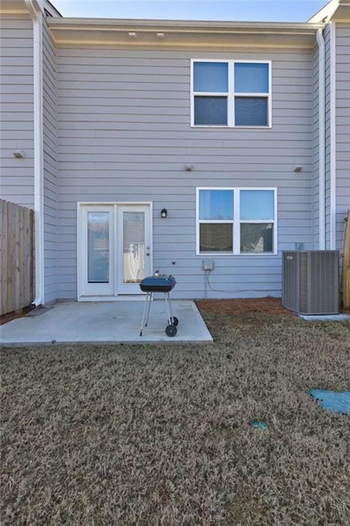 back of property with central AC unit, a patio area, fence, and a lawn