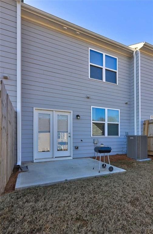 rear view of property with a yard, a patio area, fence, and central AC