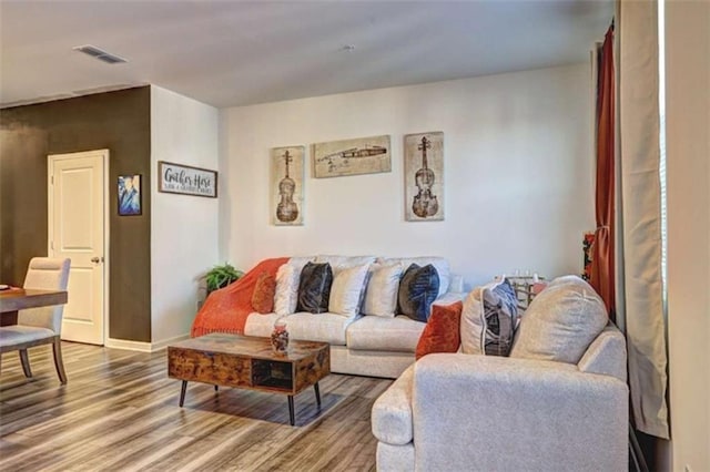 living area featuring visible vents, baseboards, and wood finished floors