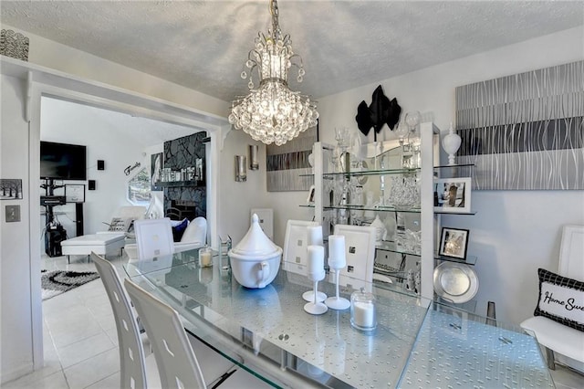 tiled dining room with a fireplace, a textured ceiling, and an inviting chandelier