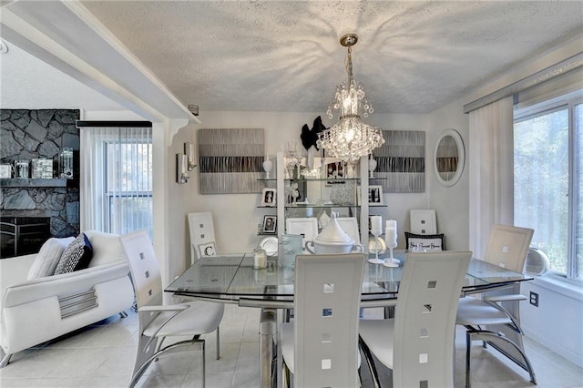 dining area featuring light tile patterned flooring, a textured ceiling, a healthy amount of sunlight, and a notable chandelier