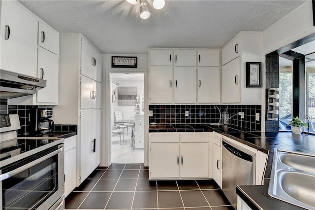 kitchen featuring decorative backsplash, white cabinets, stainless steel appliances, and range hood