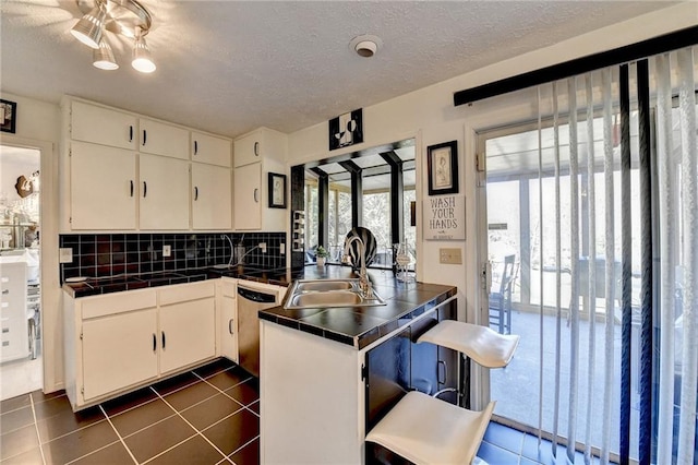 kitchen with white cabinets, dark tile patterned flooring, decorative backsplash, a textured ceiling, and kitchen peninsula