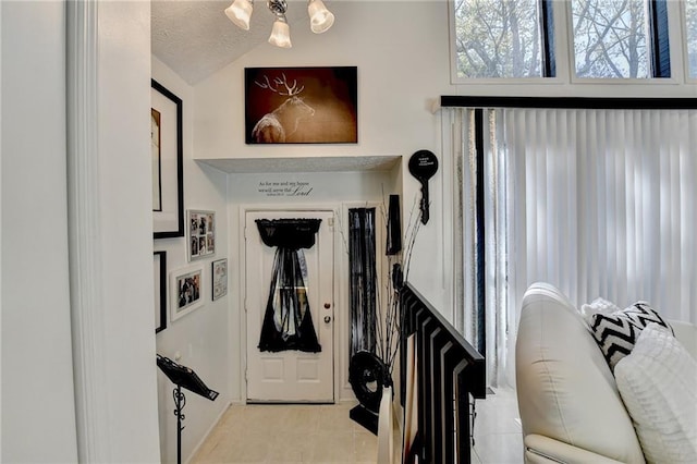 tiled foyer entrance featuring a textured ceiling, a chandelier, and lofted ceiling