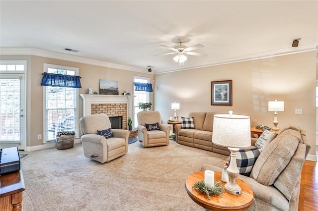 living room with a brick fireplace, plenty of natural light, ornamental molding, and ceiling fan