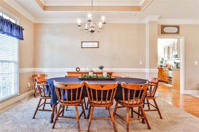 carpeted dining space with an inviting chandelier, ornamental molding, and a raised ceiling