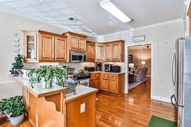 kitchen with stainless steel appliances, a breakfast bar, light wood-type flooring, and kitchen peninsula