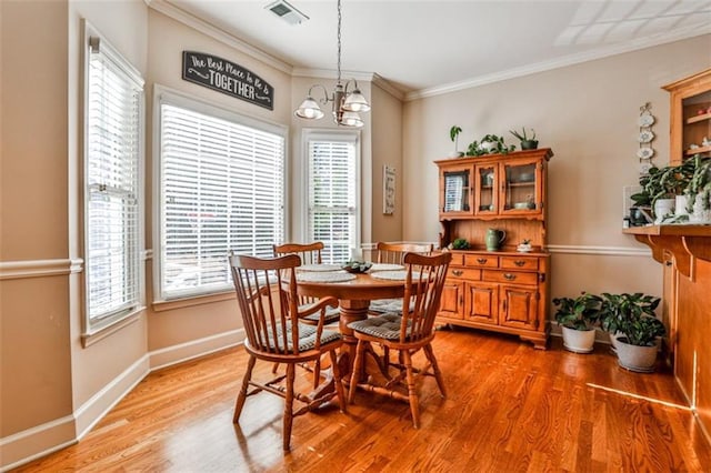 dining space featuring crown molding, wood-type flooring, and a chandelier