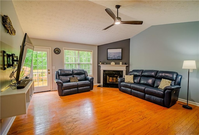 1444 Elliotts Ln, Auburn, GA 30011 - living area with ceiling fan, light wood-style flooring, a textured ceiling, a premium fireplace, and vaulted ceiling