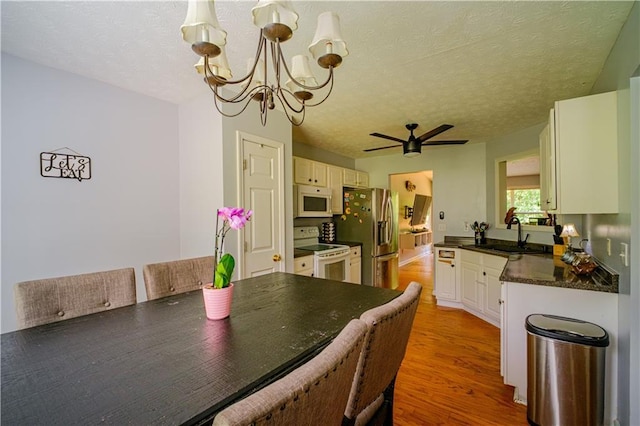 1444 Elliotts Ln, Auburn, GA 30011 - dining area with a chandelier, a ceiling fan, light wood-style flooring, and a textured ceiling
