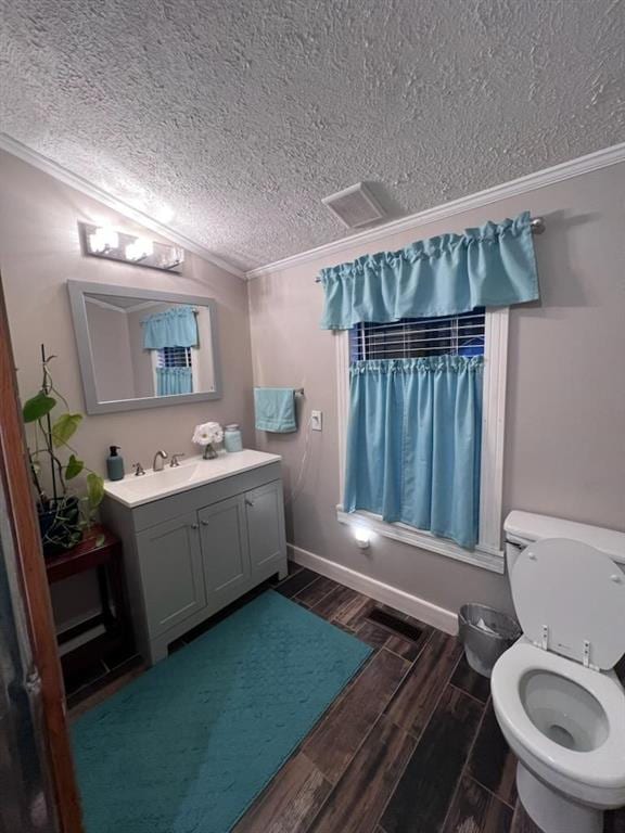 bathroom featuring vanity, a textured ceiling, hardwood / wood-style flooring, crown molding, and toilet